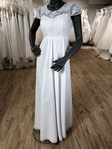 Weißes Schwangerschaftsbrautkleid aus Chiffon mit Spitzenoberteil und überschnittenen Ärmeln an einer schwarzen Schaufensterpuppe im Brautladen
