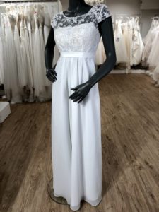 Weißes Schwangerschaftsbrautkleid mit Spitzenoberteil und überschnittenen Ärmeln an einer schwarzen Schaufensterpuppe im Brautladen