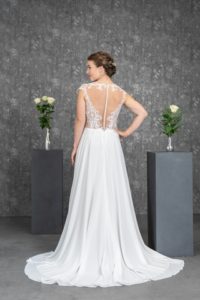 Brünettes Model mit weißem Chiffon-A-Linienenbrautkleid mit ausgefallener Tattoospitze indoor von hinten